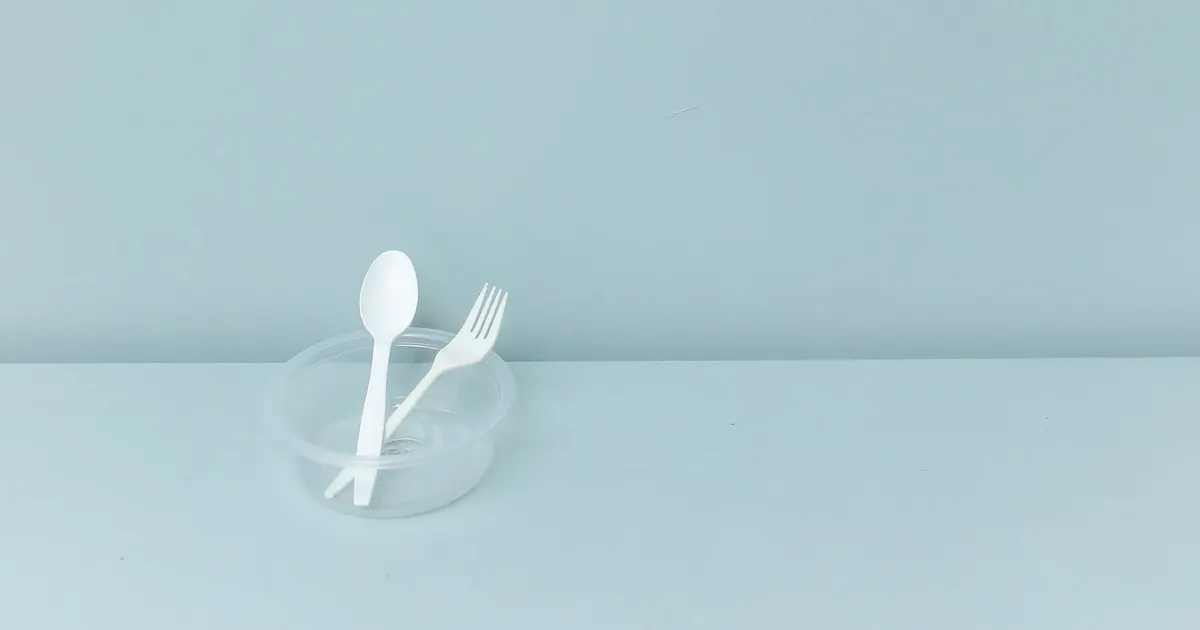 White disposable spoon and fork in a clear container, the kind of item compared in cpla vs pla cutlery