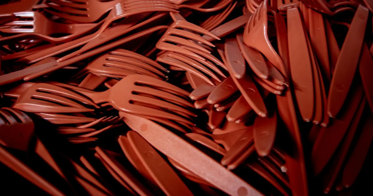 Pile of red plastic forks and knives, the kind of plastic cutlery restricted by the EU Single-Use Plastics Directive