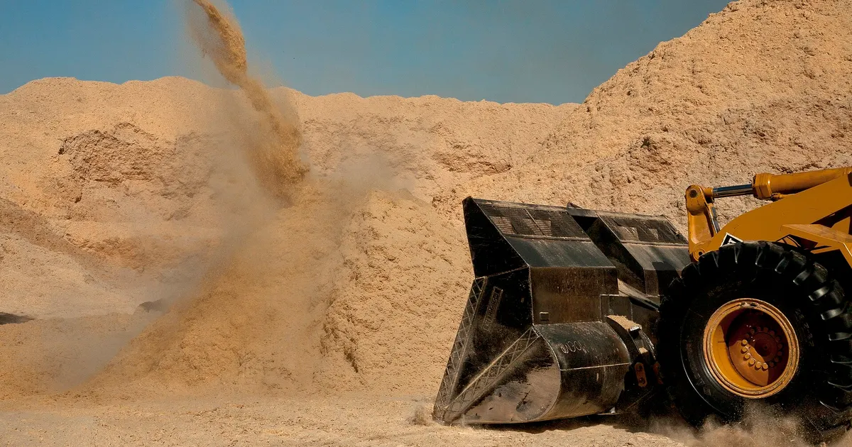 Front loader moving a pile of bagasse fiber at a sugar mill, the raw material for how bagasse tableware is made